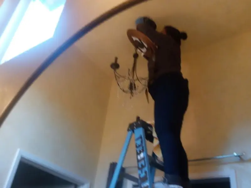 Electrician installing a chandelier in a College residence